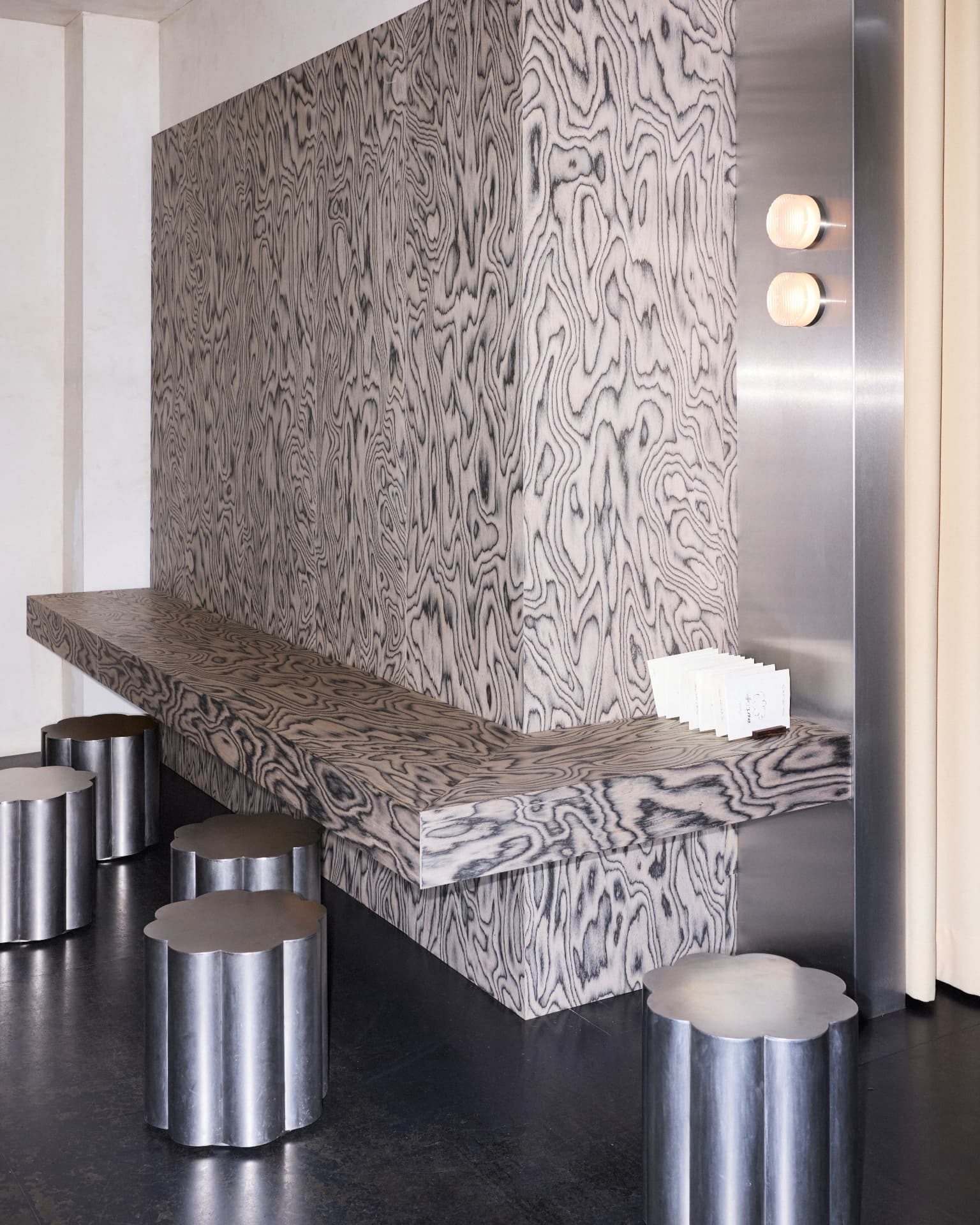 Patterned plywood bench and cloud-shaped steel stools inside DRAFT. Zürich